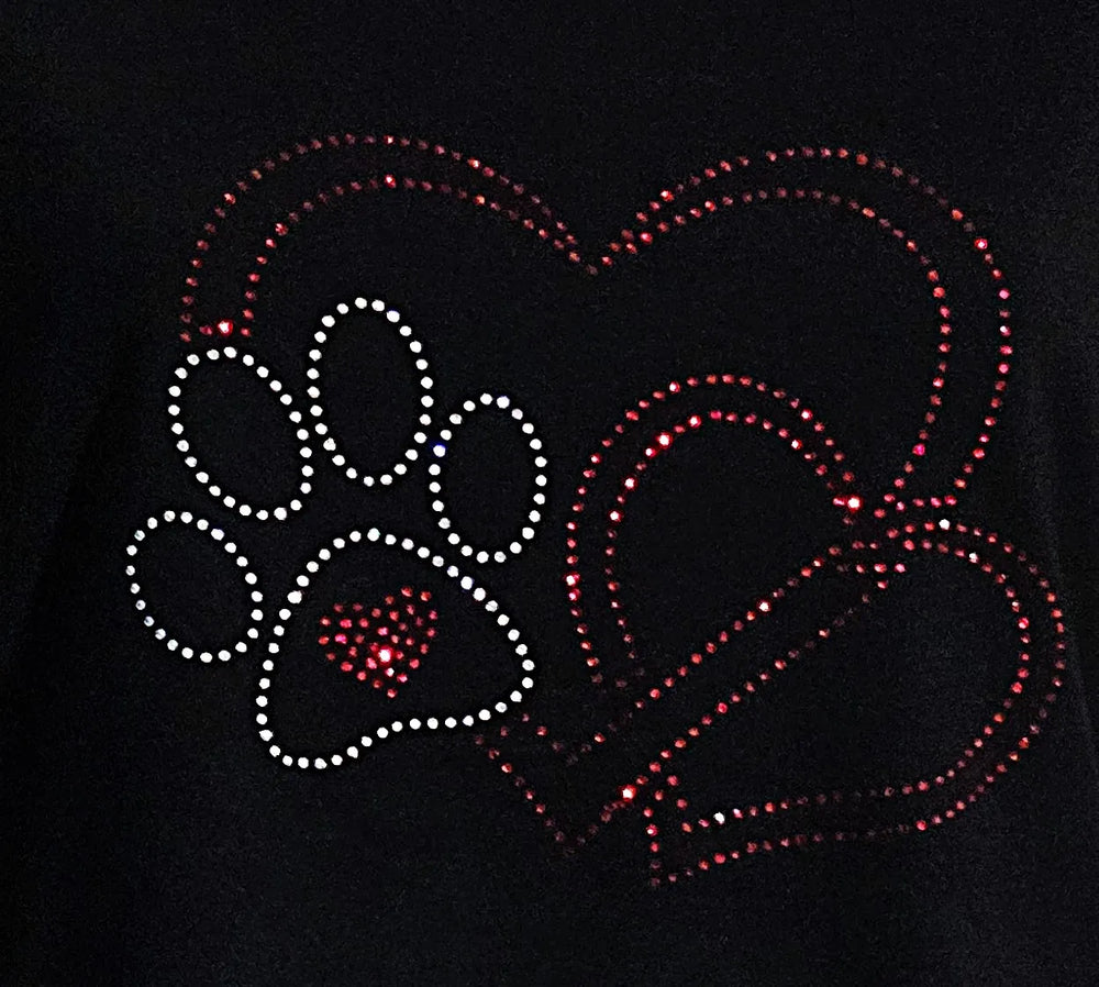 Detailaufnahme eines handgefertigten Strassmotivs mit Herz und Hundepfote auf schwarzem Damen-T-Shirt, liebevoll gestaltetes Design für Tierliebhaberinnen.
