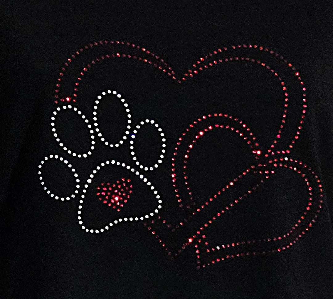 Detailaufnahme eines handgefertigten Strassmotivs mit Herz und Hundepfote auf schwarzem Damen-T-Shirt, liebevoll gestaltetes Design für Tierliebhaberinnen.