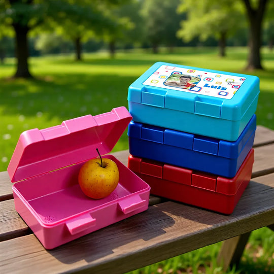 Mehrere personalisierte Brotzeitdosen in verschiedenen Farben auf einer Bank, ideal für Kindergarten und Schule