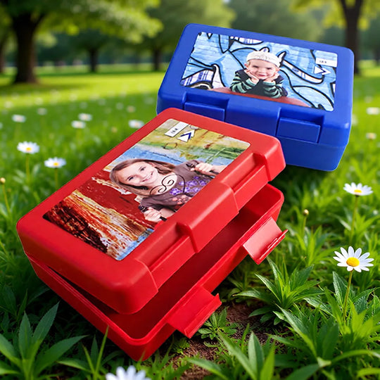 Offene rote Brotzeitdose und gestapelte personalisierte Lunchboxen in verschiedenen Farben für Kinder